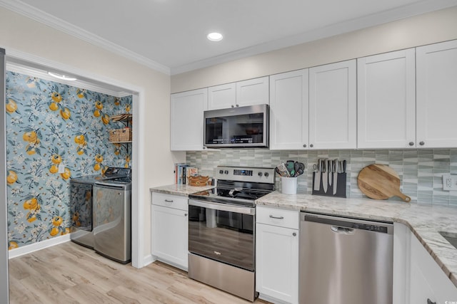 800 9th Ave S Unit A-4, North Myrtle Beach, SC 29582 - kitchen featuring baseboards, washer and clothes dryer, white cabinets, light wood finished floors, and appliances with stainless steel finishes