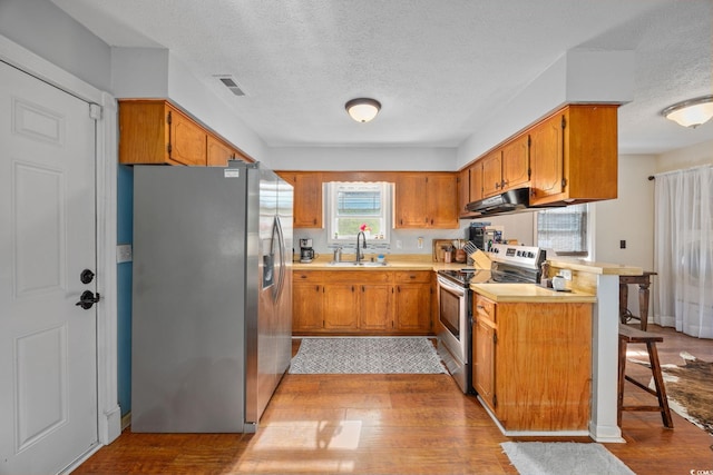 706 Birch Ln, Conway, SC 29526 - kitchen with a textured ceiling, brown cabinetry, visible vents, a peninsula, and appliances with stainless steel finishes