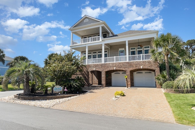 beach home with a garage, ceiling fan, a balcony, decorative driveway, and brick siding