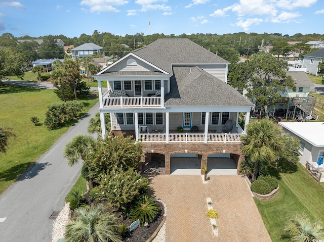 back of house featuring roof with shingles, a carport, decorative driveway, and a balcony