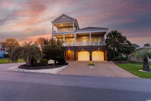 view of front of house with an attached garage, a front yard, decorative driveway, and a balcony