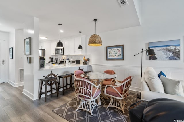 201 N Hillside Dr N Unit 307, North Myrtle Beach, SC 29582 - dining space with wainscoting, wood finished floors, and visible vents
