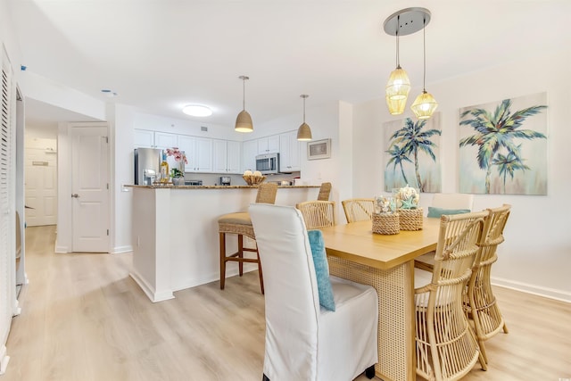 dining area with light wood-style floors and baseboards