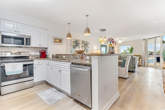 kitchen featuring white cabinets, stainless steel appliances, light wood finished floors, and a peninsula