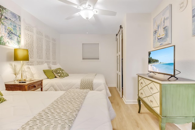 bedroom with baseboards, a ceiling fan, light wood finished floors, and a barn door