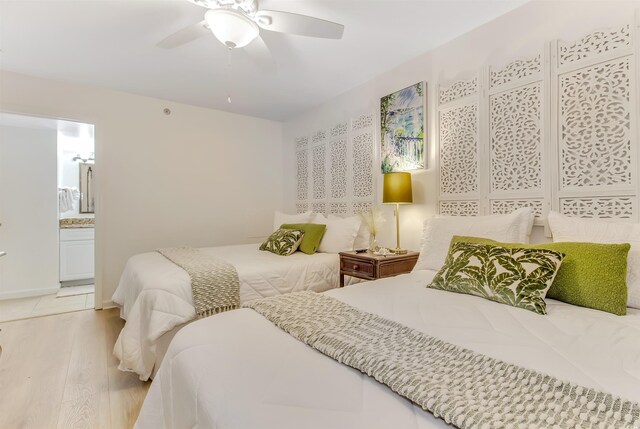 bedroom with light wood-style floors, ceiling fan, and connected bathroom