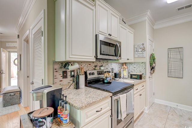 128 Puffin Dr Unit 1-E, Pawleys Island, SC 29585 - kitchen with appliances with stainless steel finishes, ornamental molding, tasteful backsplash, light stone countertops, and white cabinetry
