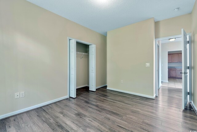148 Scotch Broom Dr Unit 201, Little River, SC 29566 - unfurnished bedroom with wood finished floors, baseboards, a closet, and a textured ceiling
