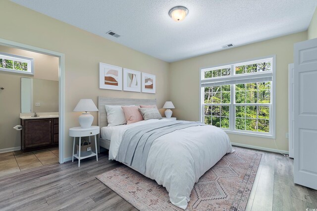 148 Scotch Broom Dr Unit 201, Little River, SC 29566 - bedroom featuring light wood finished floors, a textured ceiling, baseboards, ensuite bathroom, and a sink
