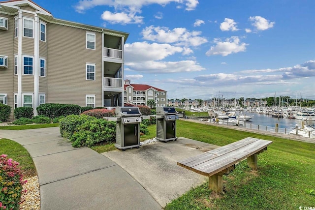 view of community with view of marina, a water view, a lawn, and a boat dock