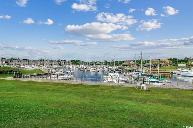 dock featuring view of marina, a yard, and a water view