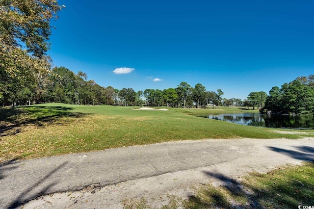 view of home's community featuring a water view, a yard, view of wooded area, and view of golf course