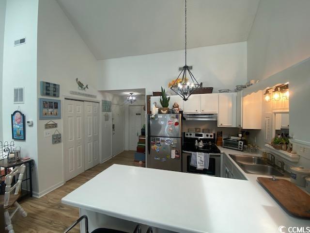1891 Colony Dr Unit 14-O, Surfside Beach, SC 29575 - kitchen with stainless steel appliances, high vaulted ceiling, a sink, a peninsula, and light wood-style floors