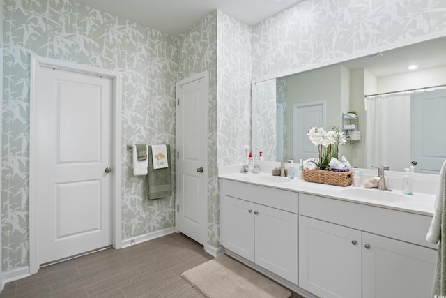 179 S Reindeer Rd, Surfside Beach, SC 29575 - full bathroom with wallpapered walls, wood finished floors, double vanity, a sink, and baseboards