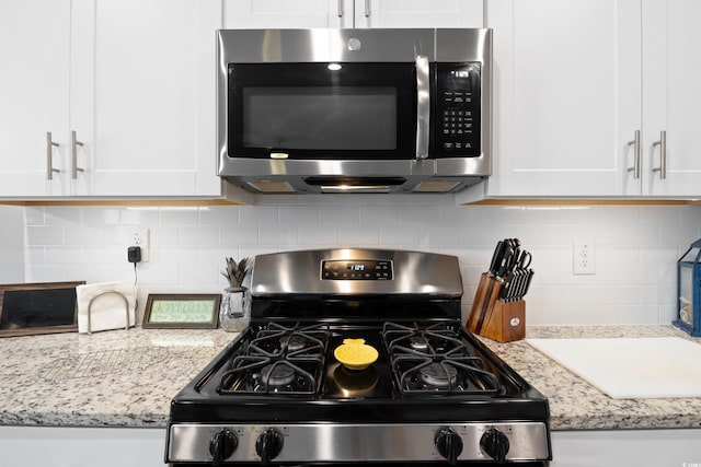179 S Reindeer Rd, Surfside Beach, SC 29575 - kitchen featuring appliances with stainless steel finishes, light stone countertops, tasteful backsplash, and white cabinetry