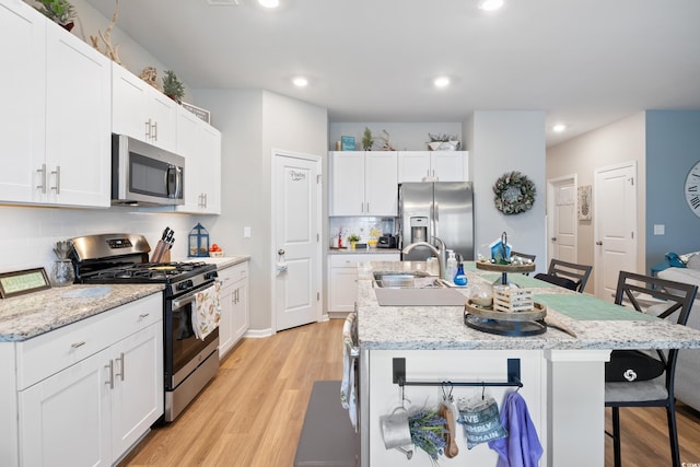 179 S Reindeer Rd, Surfside Beach, SC 29575 - kitchen with stainless steel appliances, a sink, light wood-type flooring, tasteful backsplash, and a breakfast bar area