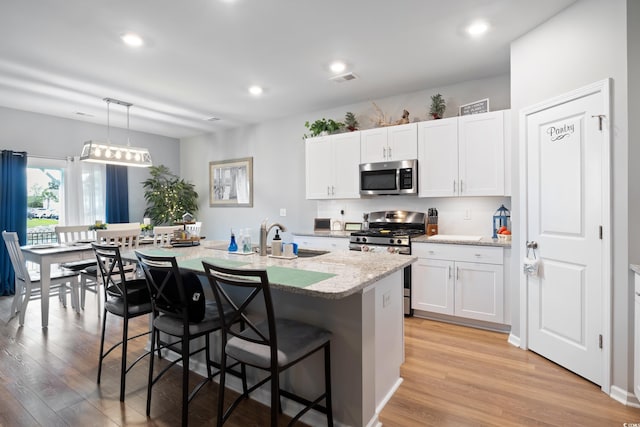 179 S Reindeer Rd, Surfside Beach, SC 29575 - kitchen with a kitchen breakfast bar, a sink, light wood-style floors, light stone countertops, and appliances with stainless steel finishes