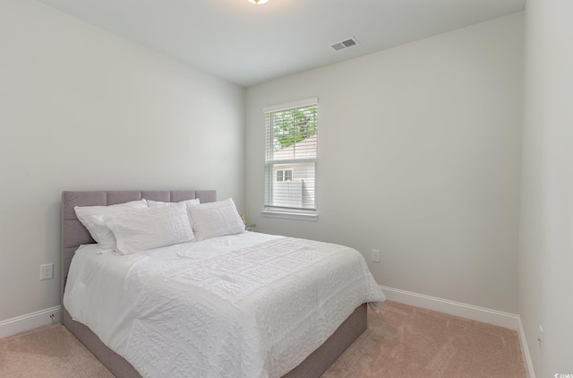 bedroom featuring baseboards, visible vents, and light colored carpet
