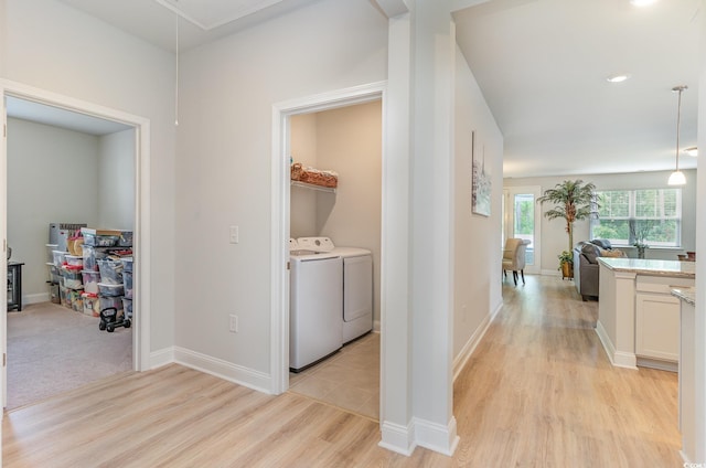 hallway featuring attic access, washer and dryer, baseboards, and light wood finished floors