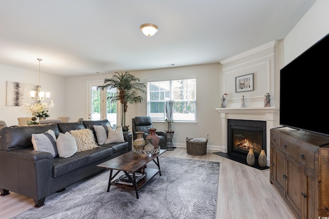 living area with light wood finished floors, an inviting chandelier, baseboards, and a large fireplace