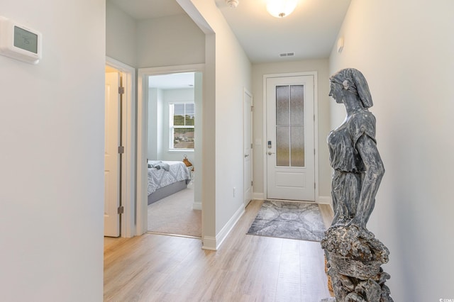doorway featuring baseboards, light wood-style flooring, and visible vents