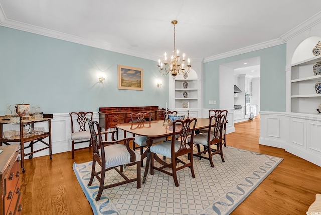 486 Lantana Cir, Georgetown, SC 29440 - dining room with built in shelves, ornamental molding, light wood-style floors, a chandelier, and wainscoting
