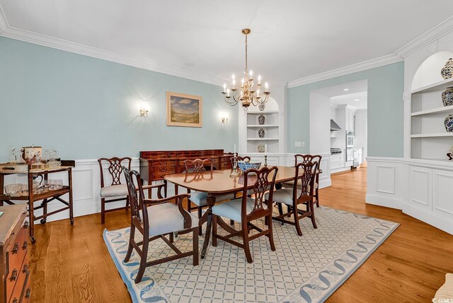 486 Lantana Cir, Georgetown, SC 29440 - dining room with built in shelves, ornamental molding, light wood-style floors, a chandelier, and wainscoting