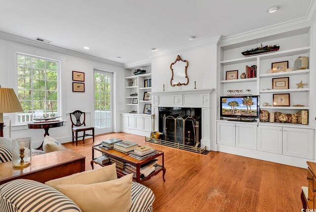 486 Lantana Cir, Georgetown, SC 29440 - living area with ornamental molding, light wood finished floors, a fireplace with raised hearth, and built in shelves