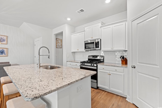 2620 Blue Crane Cir Unit 103, Myrtle Beach, SC 29577 - kitchen with stainless steel appliances, a sink, a kitchen breakfast bar, white cabinets, and light stone counters