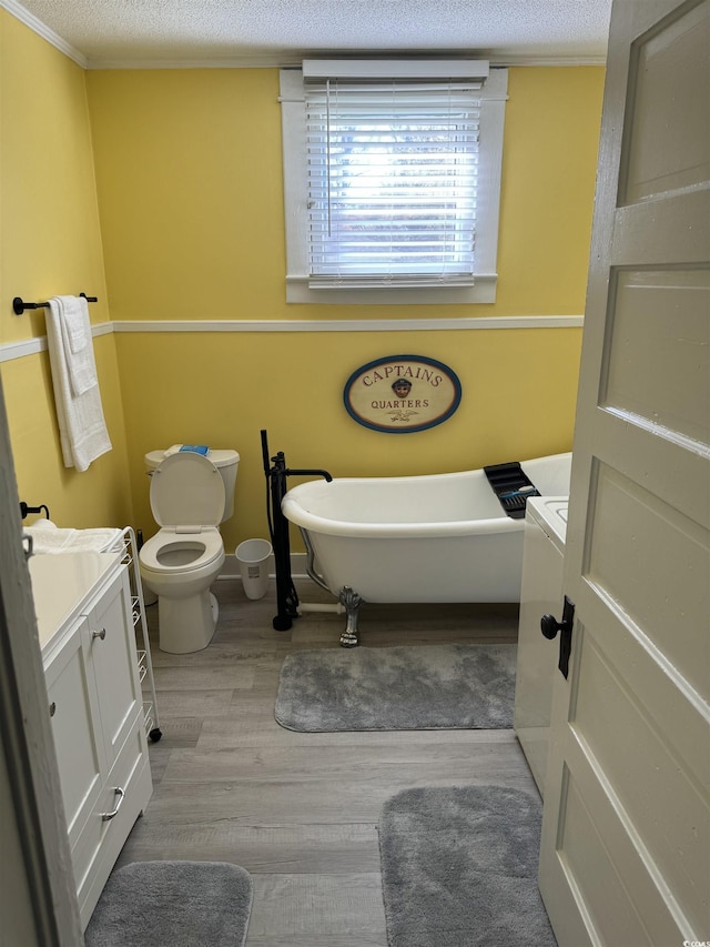 full bath with vanity, toilet, a freestanding tub, wood finished floors, and ornamental molding