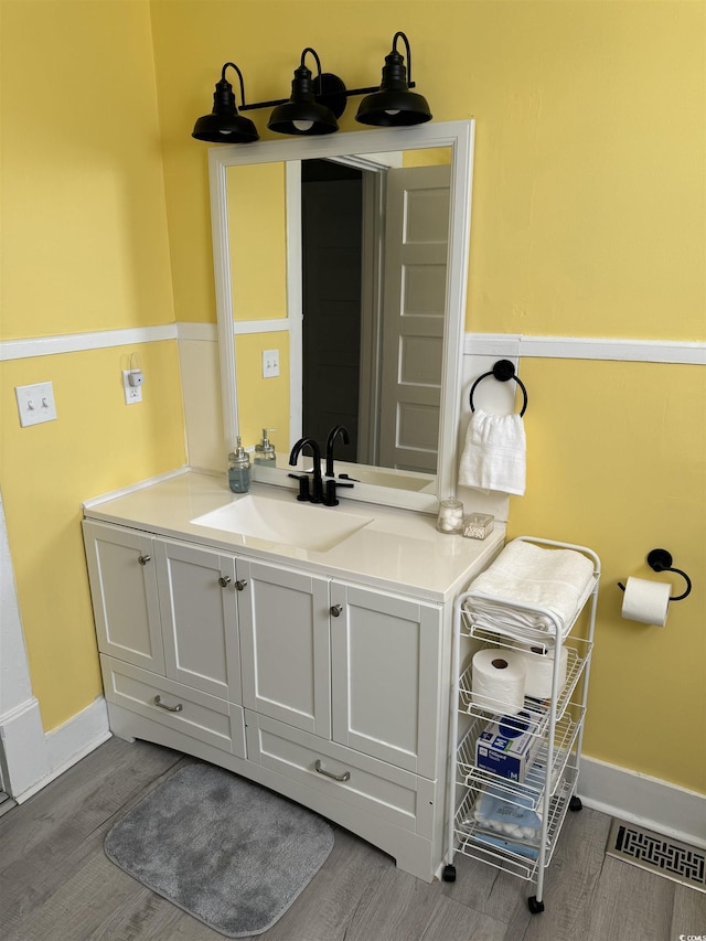 bathroom with vanity, visible vents, wood finished floors, and baseboards