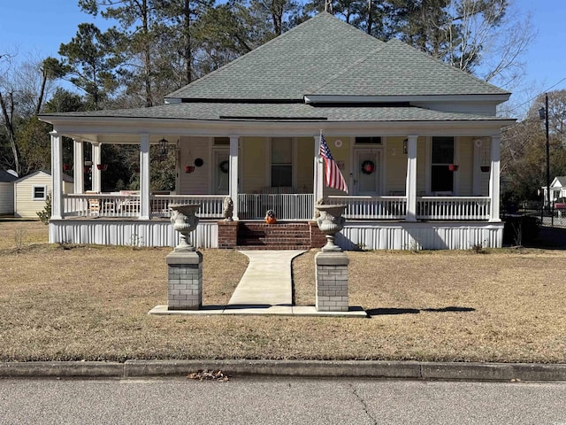 country-style home featuring a porch and roof with shingles