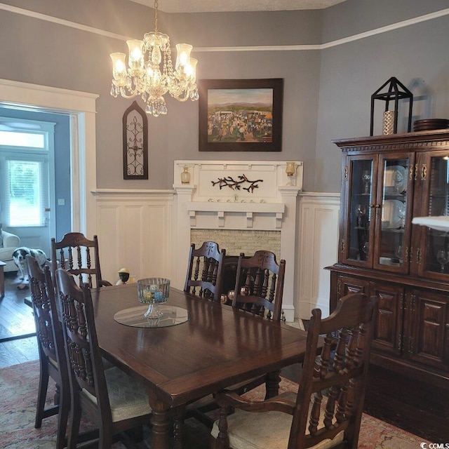 dining area featuring a decorative wall, wainscoting, wood finished floors, and a chandelier