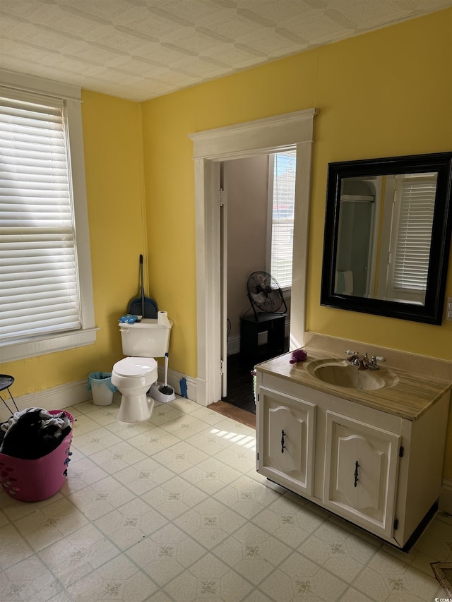 bathroom featuring toilet, vanity, and baseboards