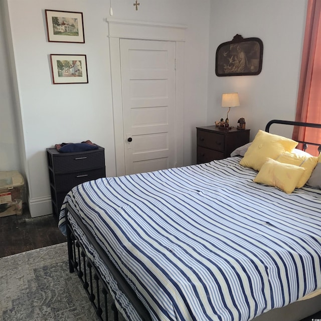 bedroom with baseboards, wood finished floors, and a closet