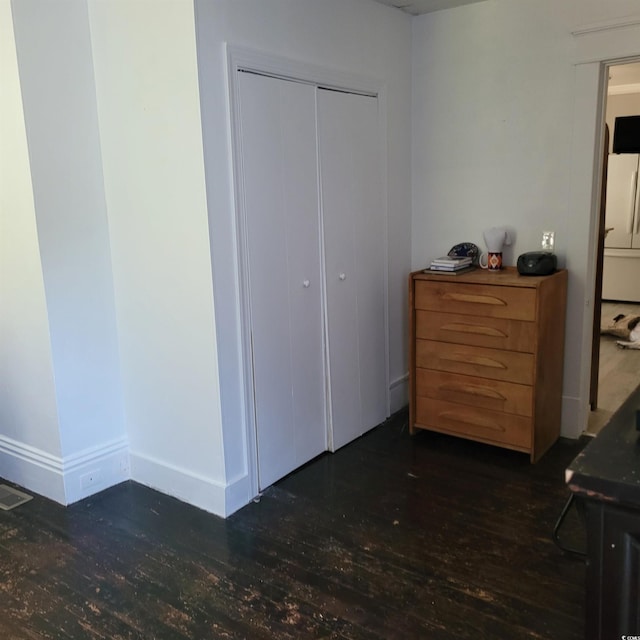 bedroom featuring freestanding refrigerator, baseboards, wood finished floors, visible vents, and a closet