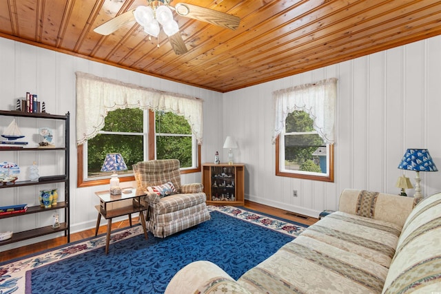 living area with wooden ceiling, plenty of natural light, ceiling fan, wood finished floors, and crown molding