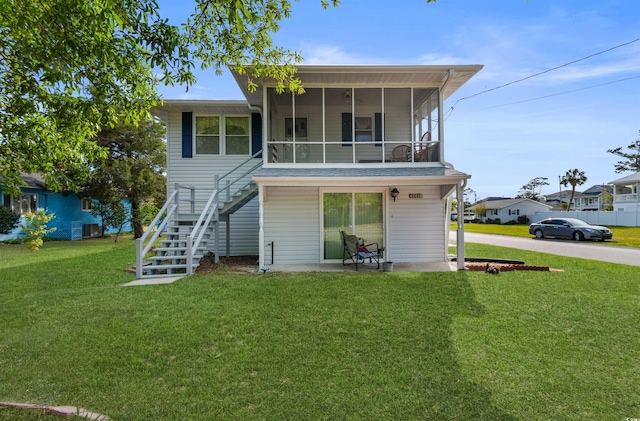 back of property with stairway, a yard, and a sunroom