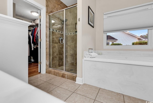 bathroom with tile patterned flooring, a shower stall, and a spacious closet