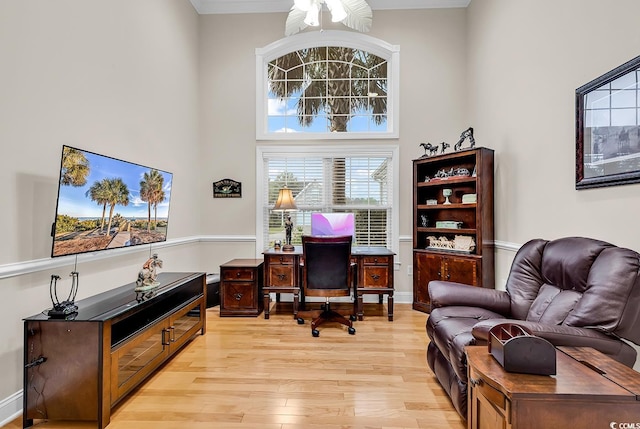 home office with ceiling fan, light wood-type flooring, and a towering ceiling