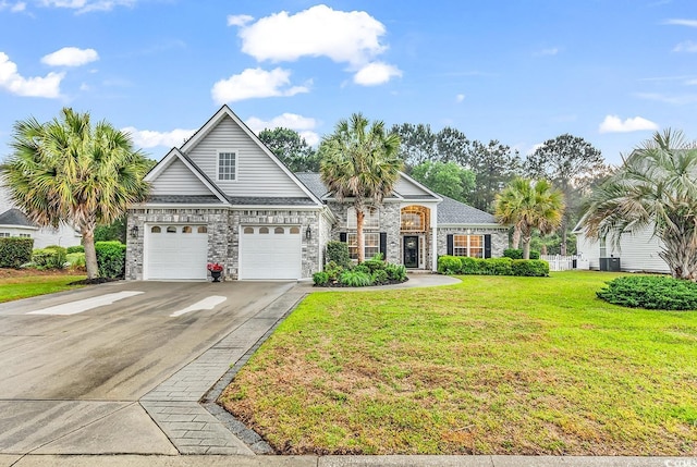 view of front facade with central AC, a front lawn, stone siding, a garage, and concrete driveway