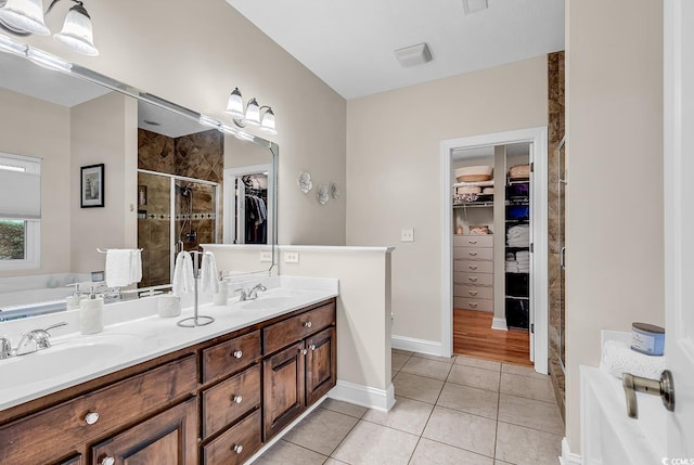 full bath with double vanity, tile patterned floors, a sink, and a stall shower