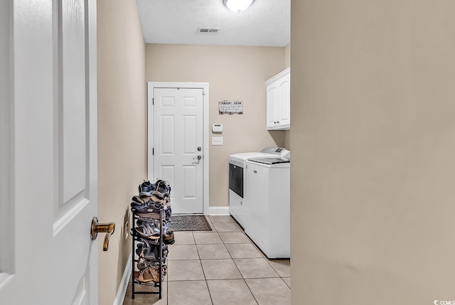 washroom with washing machine and clothes dryer, cabinet space, a textured ceiling, light tile patterned floors, and visible vents
