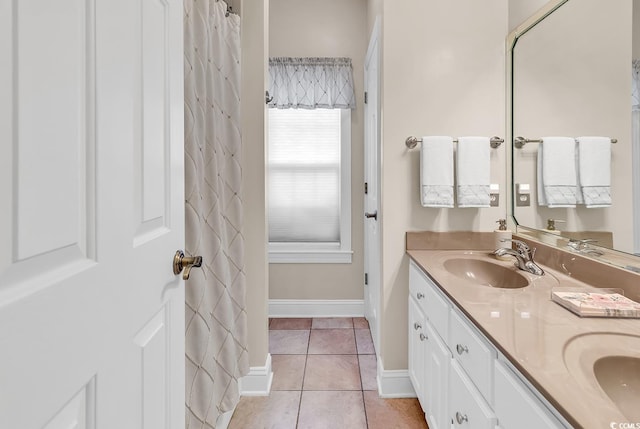 full bathroom featuring baseboards, double vanity, tile patterned floors, and a sink