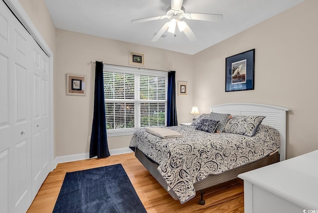 bedroom featuring a ceiling fan, baseboards, light wood finished floors, and a closet