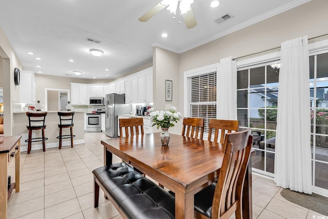 dining space with crown molding, a ceiling fan, visible vents, and light tile patterned floors