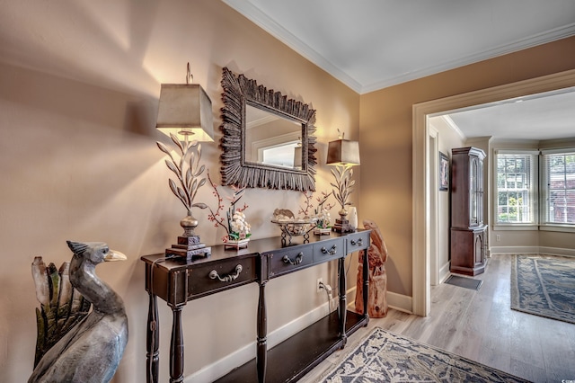 hall featuring baseboards, ornamental molding, and wood finished floors