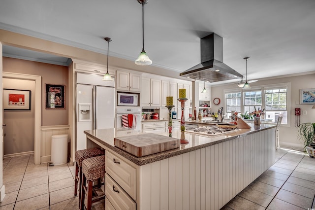 kitchen featuring a sink, built in appliances, light tile patterned floors, island range hood, and ornamental molding