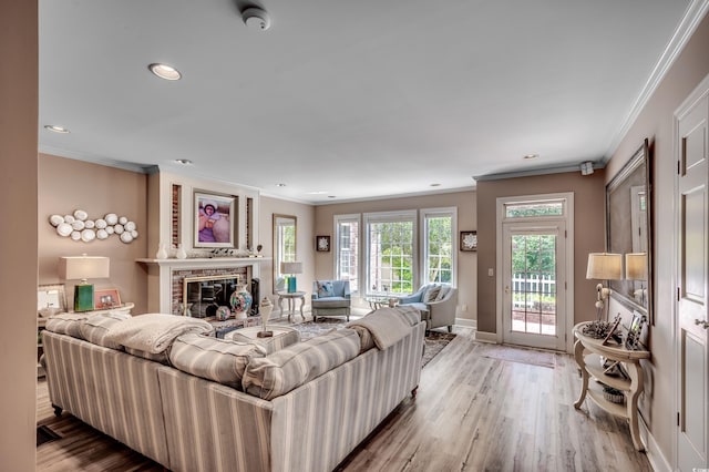 living room featuring crown molding, baseboards, a brick fireplace, and wood finished floors
