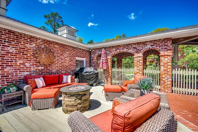 view of patio / terrace with fence, an outdoor living space with a fire pit, a wooden deck, and a grill